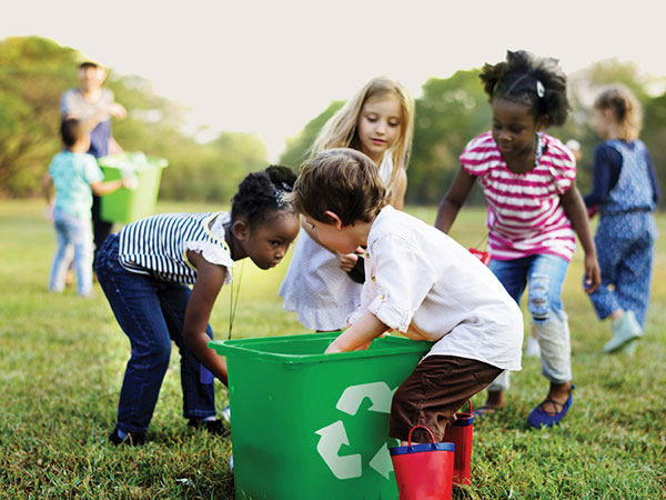 Children putting rubbish in recycle bin